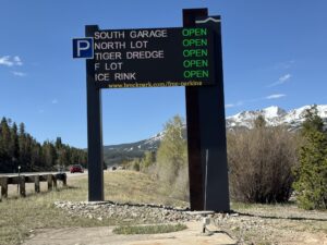 Full-colour LED parking availability sign in Breckenridge, Colorado listing South Garage, North Lot, Tiger Dredge, F Lot and Ice Rink all open, with snow-capped mountains behind