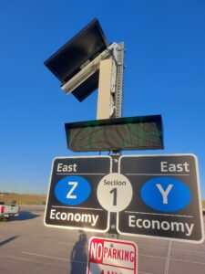 Solar-powered LED parking availability sign in the East Economy lot at Denver International Airport, its solar array lit by sunrise