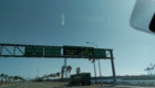 Overhead LED message boards at the Port of Los Angeles directing traffic to APM Terminals Pier 400 with seat belt and chassis restrictions